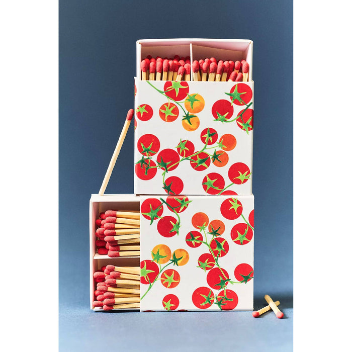 Tomato-printed match boxes with red-tipped matches stacked and displayed against blue background