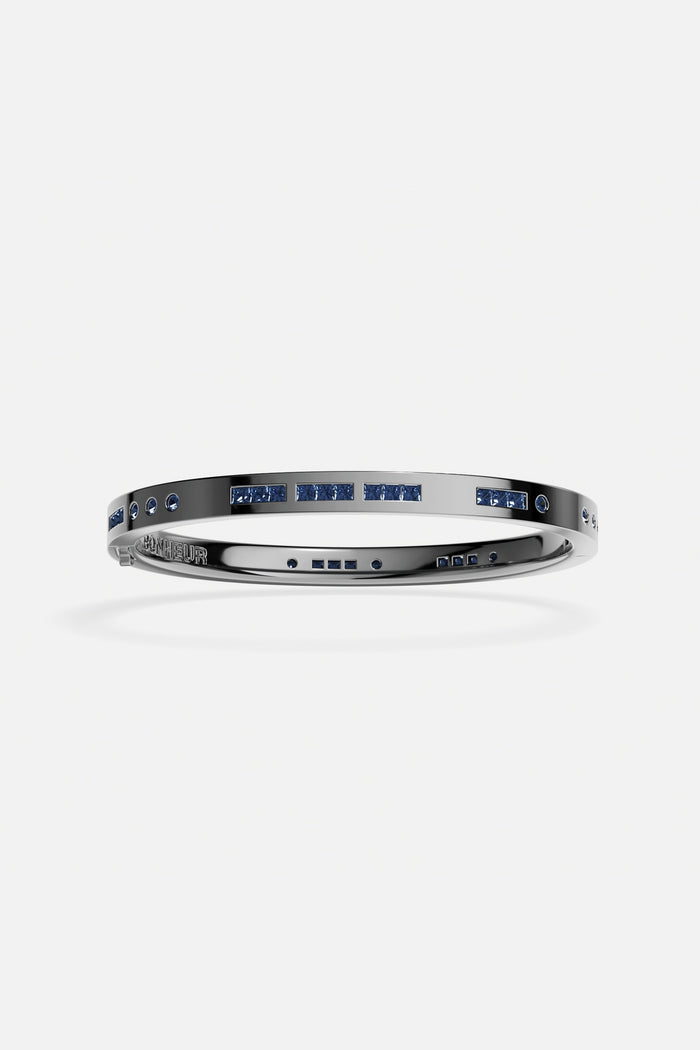 APM Bangle in rhodium finish with deep blue stones, bold and effortlessly modern.
