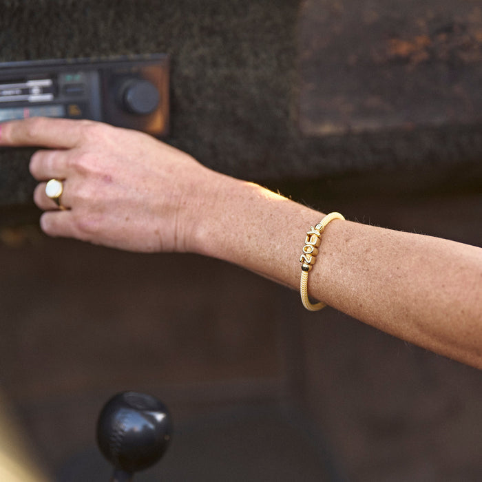 Hand with a gold bracelet and ring on a blurred background