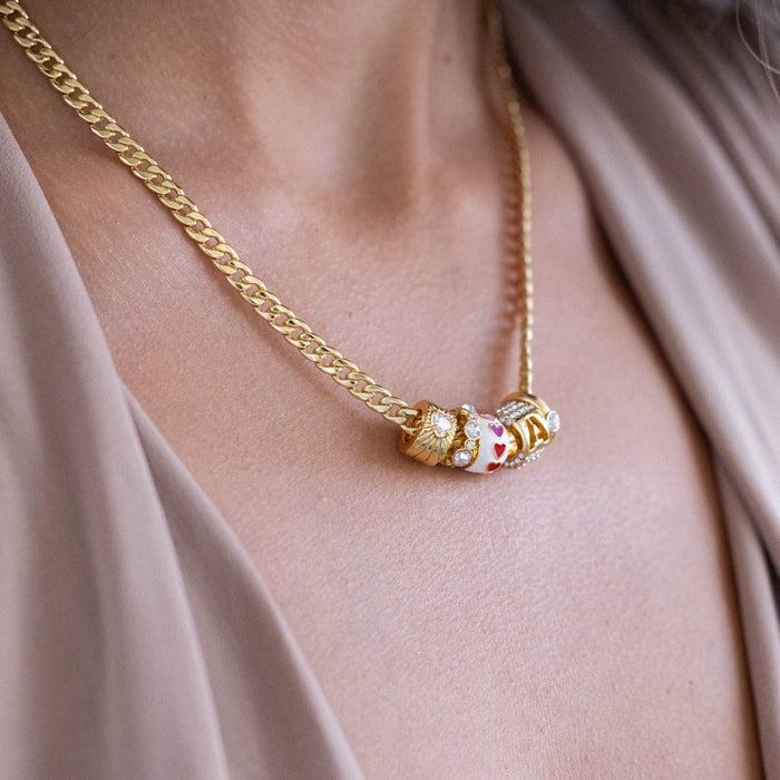 Gold necklace with a decorative clasp on a person wearing a beige top.