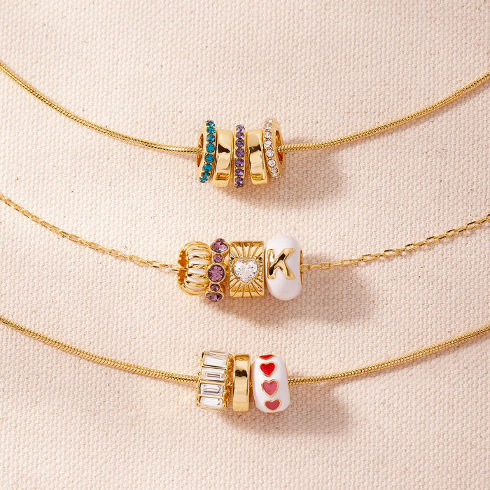 Three gold necklaces with decorative beads on a beige background