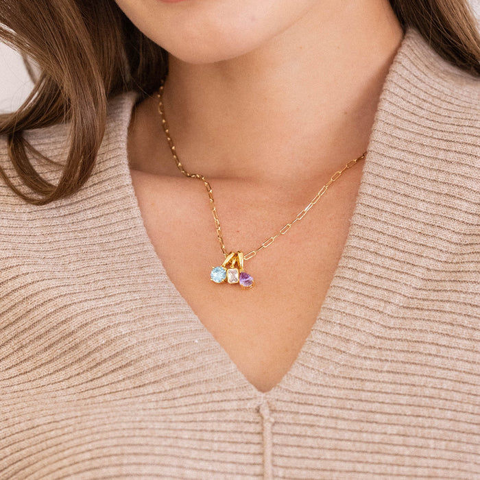 Woman wearing a necklace with a heart pendant on a plain background