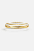 APM Bangle in golden color, twisted edges and crystal shimmer, effortlessly refined.