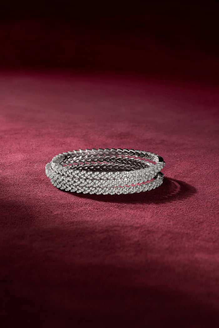 APM Monaco bangles in rhodium finish, sparkling with quiet confidence on velvet.