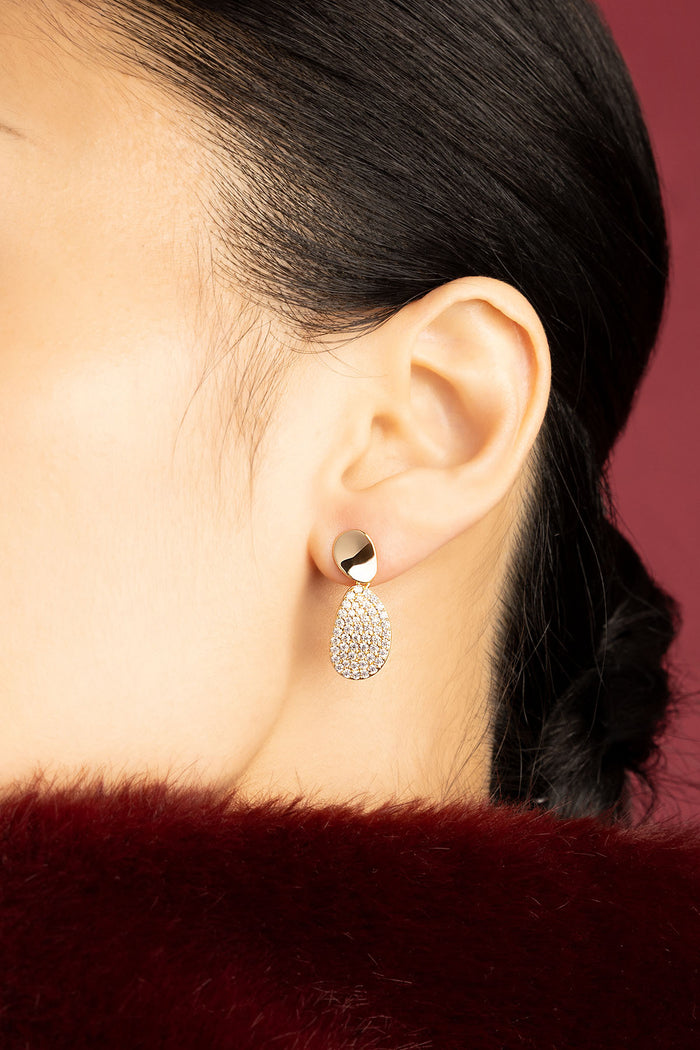 Woman wearing APM Earrings, a golden glow of quiet elegance.