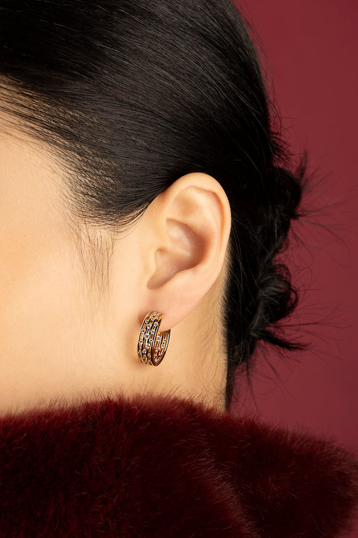 Woman wearing APM Monaco hoop earrings, a golden whisper of quiet allure.