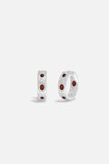 APM Hoop Earrings in rhodium finish, deep red accents glowing with quiet elegance.