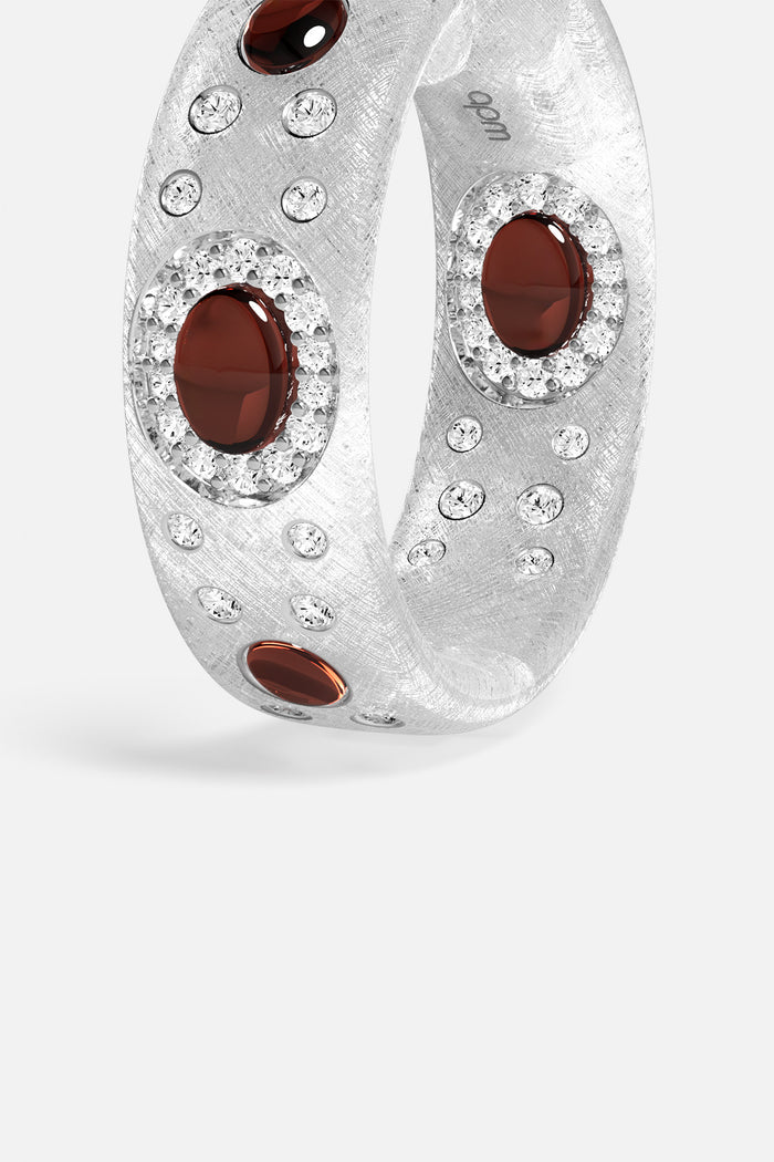 APM Ring in rhodium finish, deep red stones scattered with quiet brilliance.