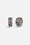 APM Monaco hoop earrings, deep red glow within a smoky rhodium finish, quietly bold.