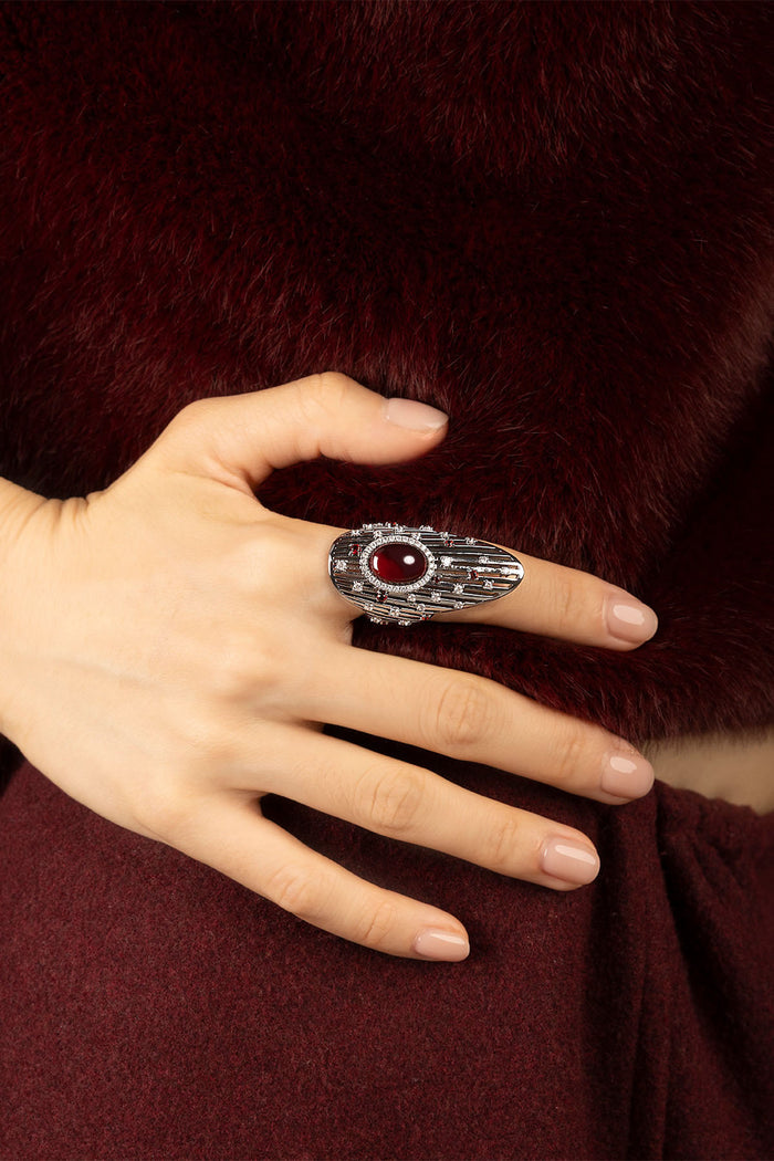 Woman wearing APM Monaco ring, a bold red gem glowing against rhodium finish.