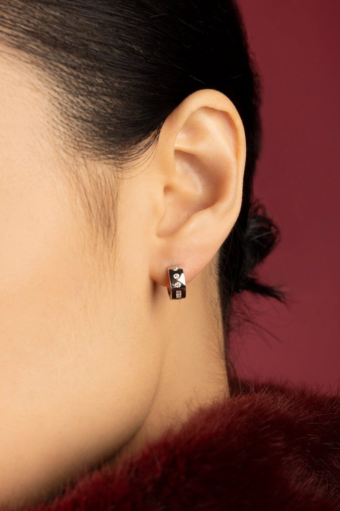 Woman wearing APM Monaco hoop earrings, a whisper of modern elegance in rhodium finish.
