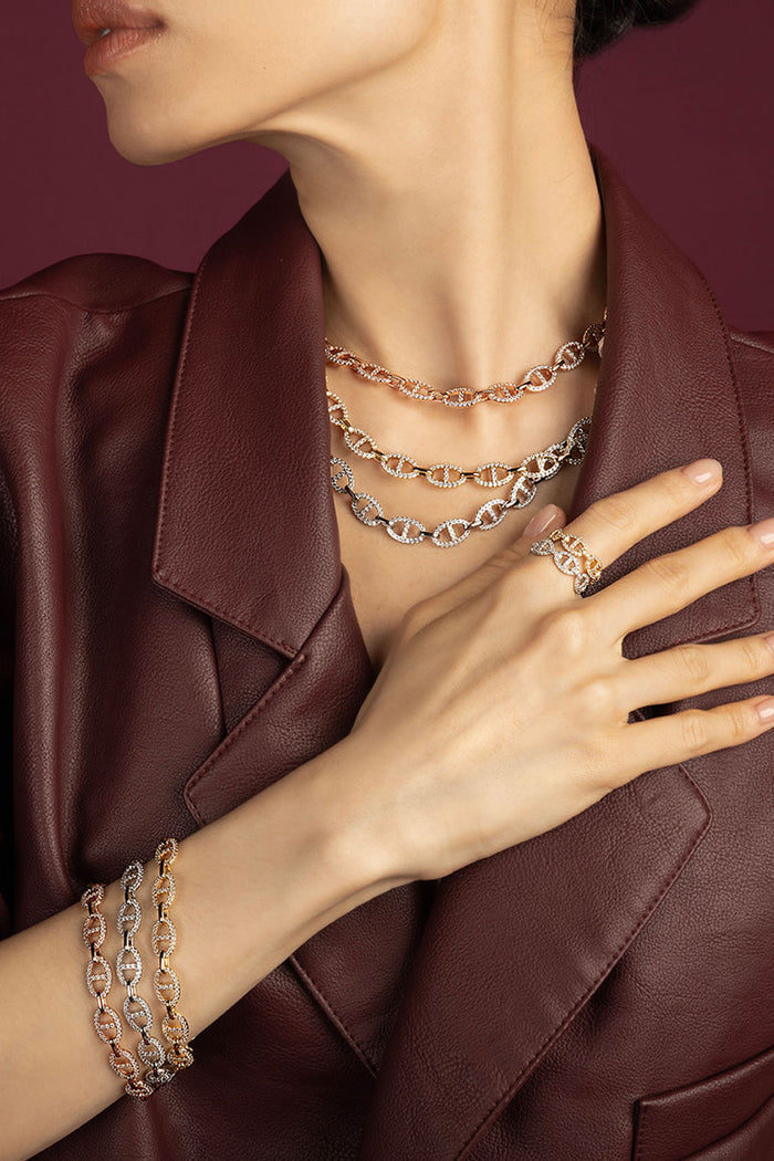 Woman wearing APM Monaco chain necklaces, bracelets and ring, layered bold elegance in burgundy leather.