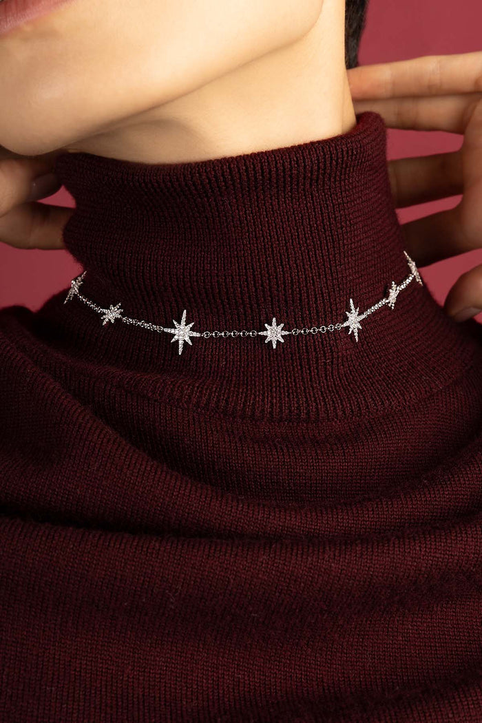 Woman wearing APM Météorites Necklace, a constellation of stars glowing against burgundy.