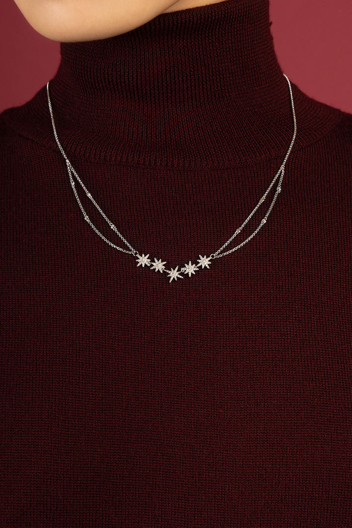Woman wearing APM Météorites Necklace, a constellation of stars glowing softly on burgundy.