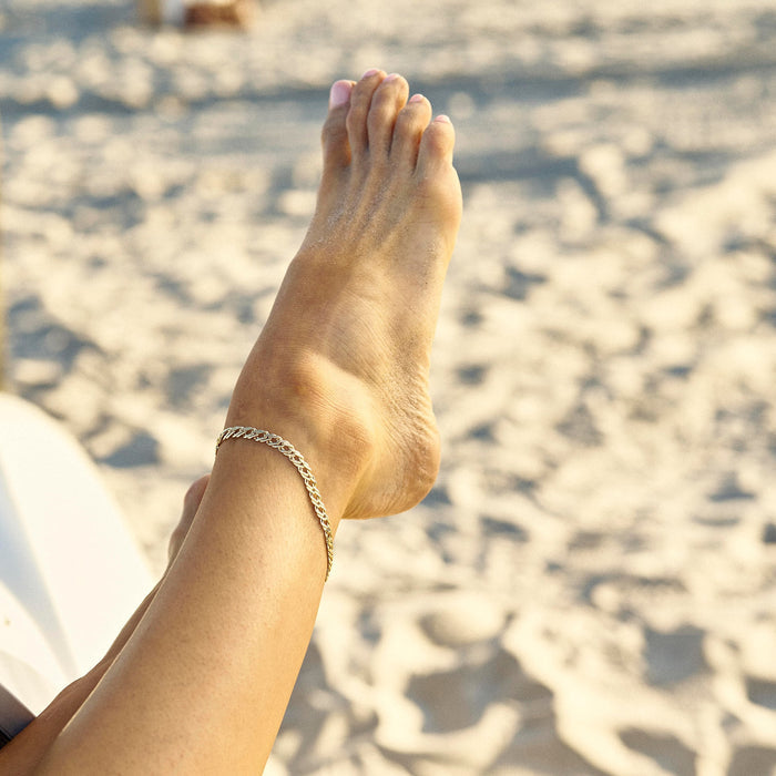 Person's foot with a anklet on a beach