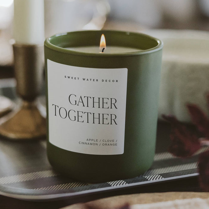 Green soy candle labeled Gather Together with apple, clove, cinnamon, orange scents in styled home decor setting
