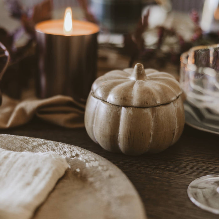 Pumpkin spice soy candle in decorative jar displayed on wooden table with fall décor and candles