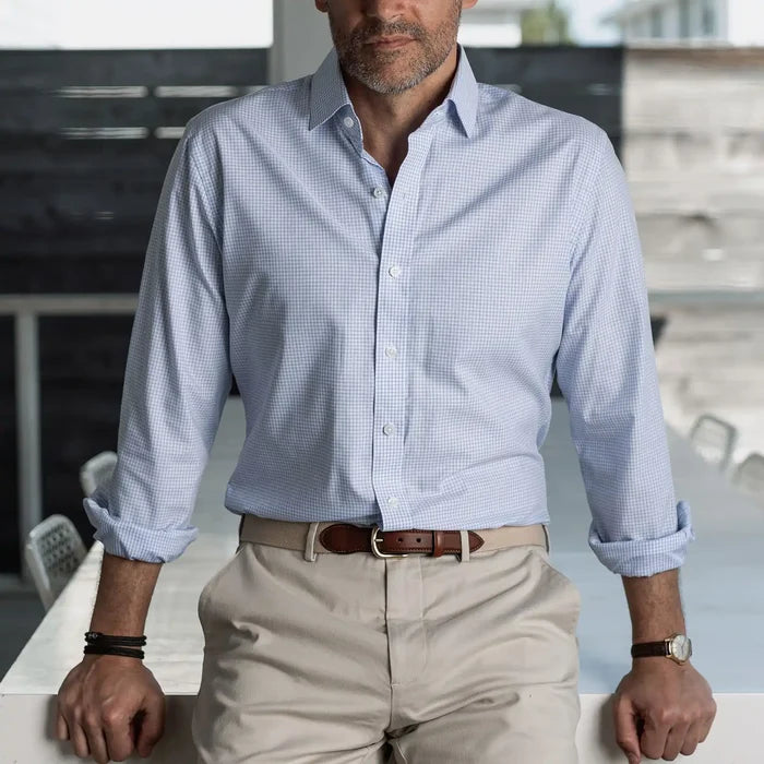 Man wearing a light blue checkered shirt and beige pants in an indoor setting