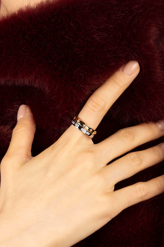 Woman wearing APM Monaco stacked rings, a whisper of stars against burgundy softness.