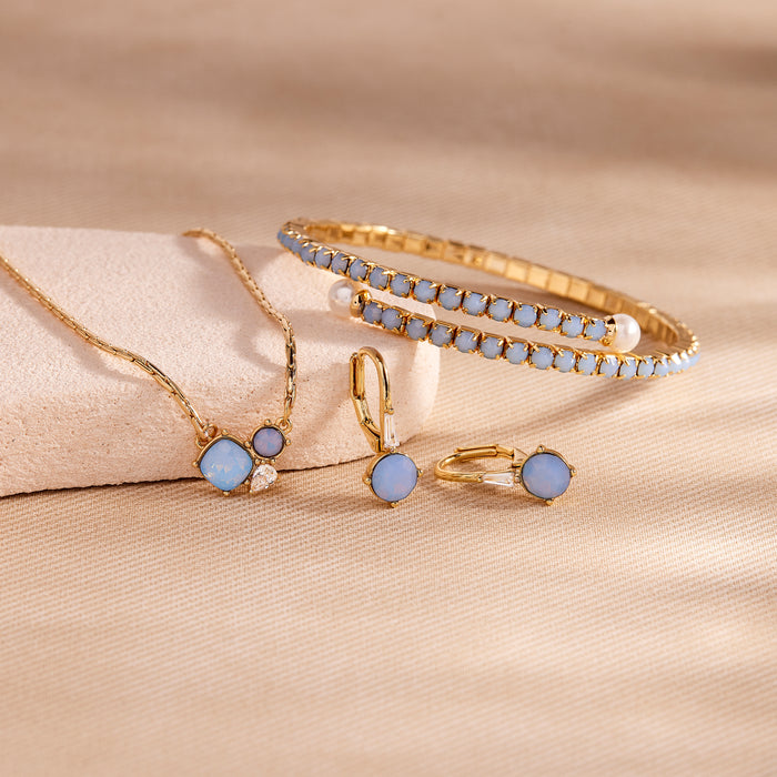Gold jewelry set with blue stones on a beige fabric background
